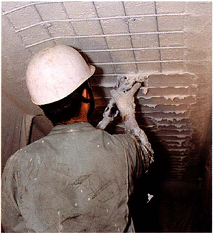 作業員が天井面へ圧送材を塗り付けている施工状況